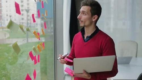 Gestionnaire réfléchi avec ordinateur portable prenant des notes sur la fenêtre