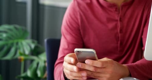Man Working at Desk Using Phone and Computer