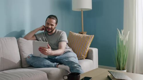 Smiling Man Using Tablet on Couch at Home