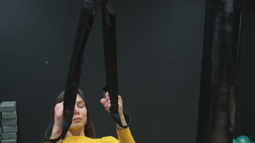 Young Fit Woman in Yellow Top Doing Push Ups with Trx Fitness Straps in the Gym