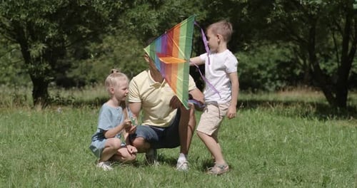Father and Children Preparing a Kite in Park