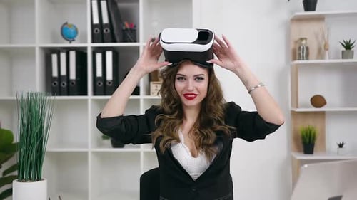 Woman with Long Wavy Hair and Bright Make-up Using Virtual Reality Headset in Her Office Room