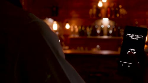 Dolly Shot of Waiter Using His Phone To Turn on the Lights in the Restaurant