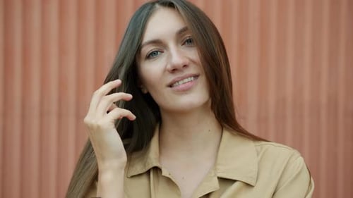 Slow Motion Portrait of Charming Young Woman Playing with Hair Smiling and Looking at Camera