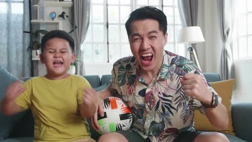 Father and Son Cheerfully Watching Sports at Home
