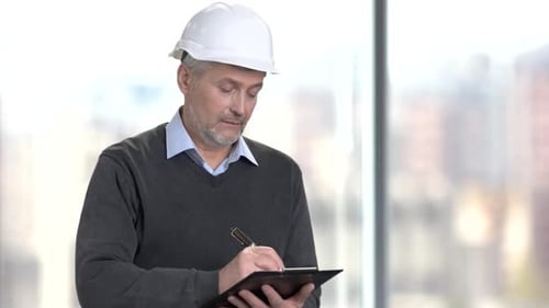 Mature Foreman Making a Note on Clipboard.