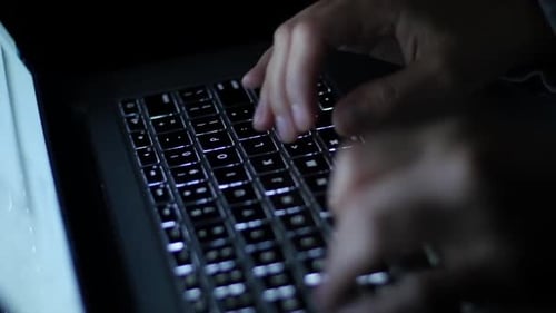 Hands Typing on Illuminated Laptop Keyboard at Night