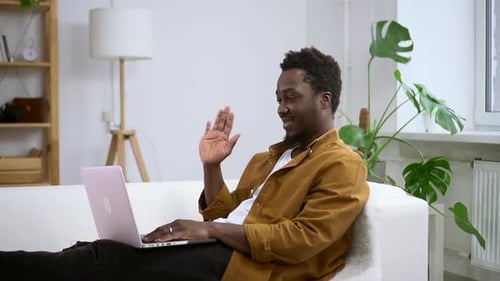 Man Waving During Video Call on Laptop