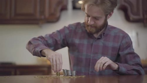 Man Counting and Stacking Coins on Table