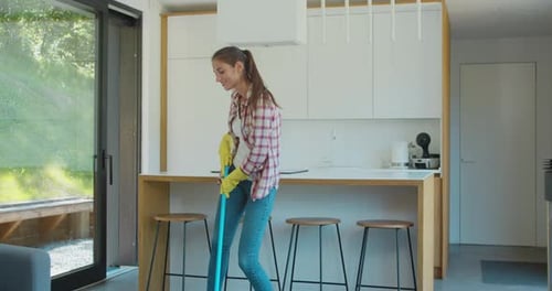 Woman Mopping and Singing in Modern Kitchen