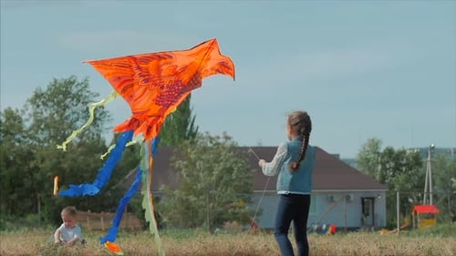 Rückansicht Kinder spielen mit einem Drachen, einem kleinen Mädchen und einem Jungen lassen eine fliegende Schlange auf der Wiese