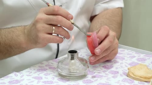 Dentist Working on Dental Mold with Tool and Flame