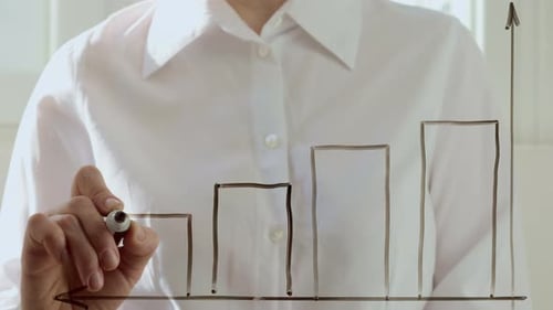 A business woman draws a financial chart and a falling down arrow on the glass. The concept of risk