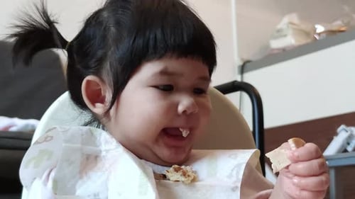 Adorable Child Eating Snack in High Chair