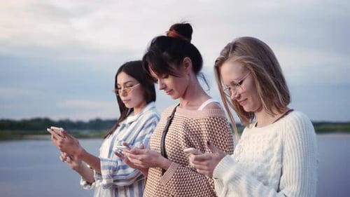 Three Women Using Phones Outside