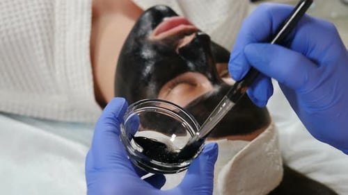 Preparation for Cosmetic Procedure in Beauty Clinic. Cosmetologist Applies Carbon Compound on Skin