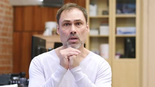 Adult Man Standing Indoors With Clasped Hands