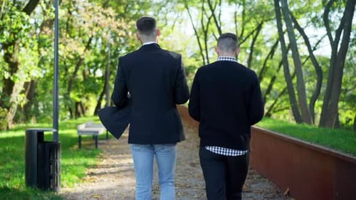Tracking Shot Two Caucasian Young Men Walking in Sunny Park Talking