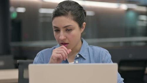 Nahaufnahme einer indischen Frau, die hustet, während sie einen Laptop benutzt
