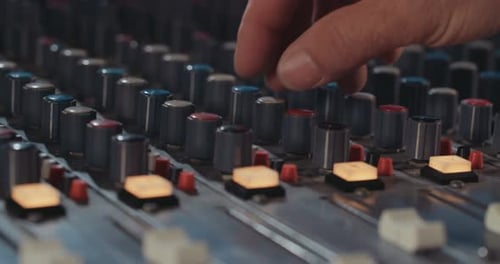 Sound engineer working in a recording studio with a sound console and microphones