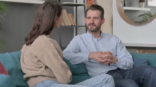Pareja teniendo una conversación seria mientras está sentada en el sofá