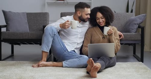 Cozy Couple Relaxing Indoors with Laptop and Drinks