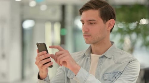 Young Adult Man Using a Phone Indoors
