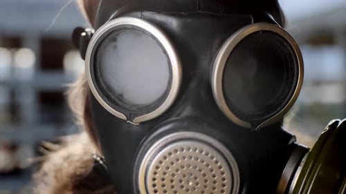 Nahaufnahme des Auges einer Frau mit Gasmaske, die durch Rauch in die Luft gesprengt wird