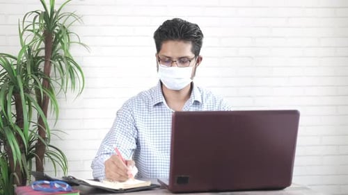 Adult Working at Desk with Laptop and Notebook