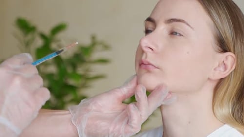 Primer plano recortado de una hermosa mujer joven que recibe inyecciones en los labios por un cosmetólogo profesional