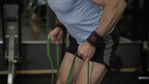 Close up image of man doing exercise with elastic band at the gym.