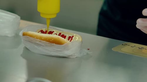 Adding Mustard to a Hot Dog in Plastic Bag