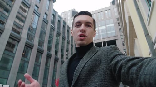 Smiling Young Business Man Making Selfie Video Call Standing Outdoor at Business District. Portrait