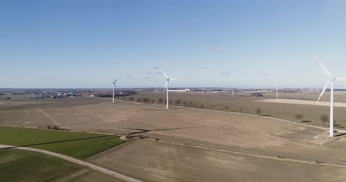 Beautiful aerial sunset landscape with lake and windmills or wind turbine on wind farm in rotation t