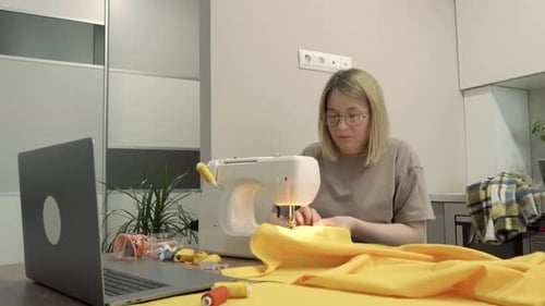 Woman Sewing Yellow Fabric at Sewing Machine