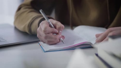 Hands of Millennial Caucasian Boy Writing in Workbook. Close-up of Male Palm with Pen. Diligent