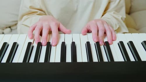 Woman hand musician playing electronic piano at home on sofa in living room, close-up