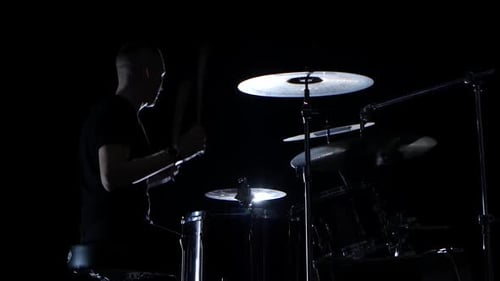 Gute Musik in der Aufführung eines professionellen Schlagzeugers. Seitliche Ansicht. Schwarzer Hintergrund