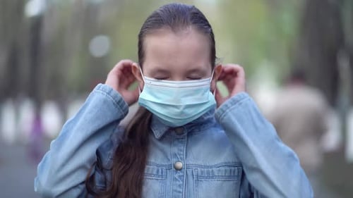 Girl Puts On Face Mask in a Park