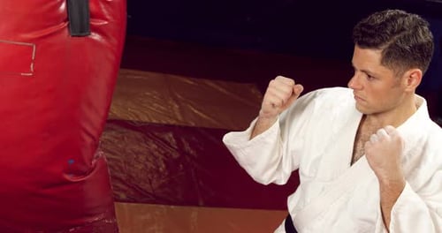 Man Practices Martial Arts Punching Heavy Bag