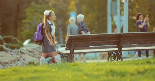 Kleines Mädchen aus einer Grundschule schlendert bei Sonnenuntergang durch den Park