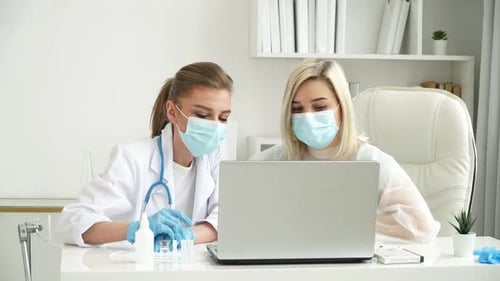 Team of Female Doctors in Protective Masks Discuss Patients Diagnosis at Laptop in Clinic