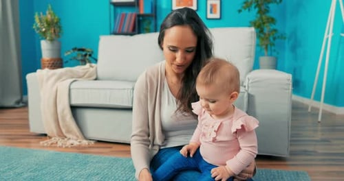 Girl is Sitting on Carpet with Mother Putting Together Tower of Blocks Daughter is Destroying