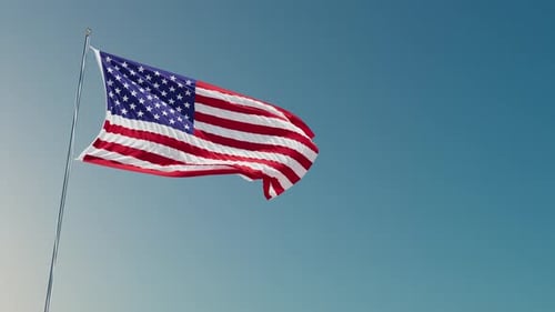 Waving American Flag on Flagpole Against Blue Sky
