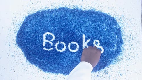 Hand Writes "Books" with White Powder on Blue