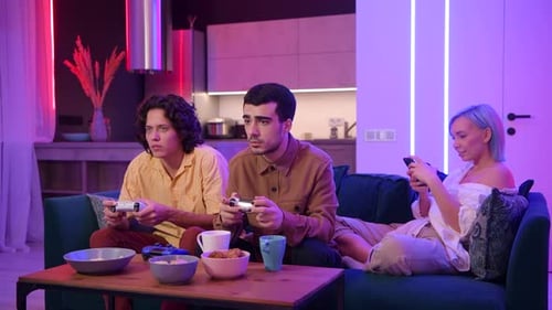 Young Adults Playing Video Games on Couch at Night