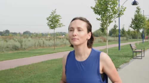 Woman Jogging Through Park on a Sunny Day