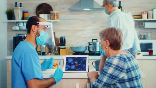Healthcare Worker Explains to Senior Woman in Kitchen