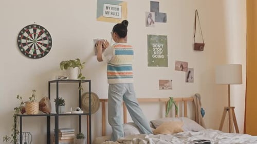 Teenage Girl Hanging Posters on Wall