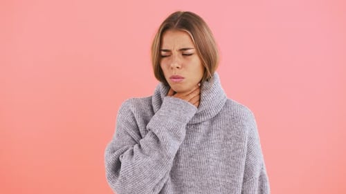 Female Has a Sore Throat and Coughing Looking Unhappy and Ill While Posing Against Pink Studio
